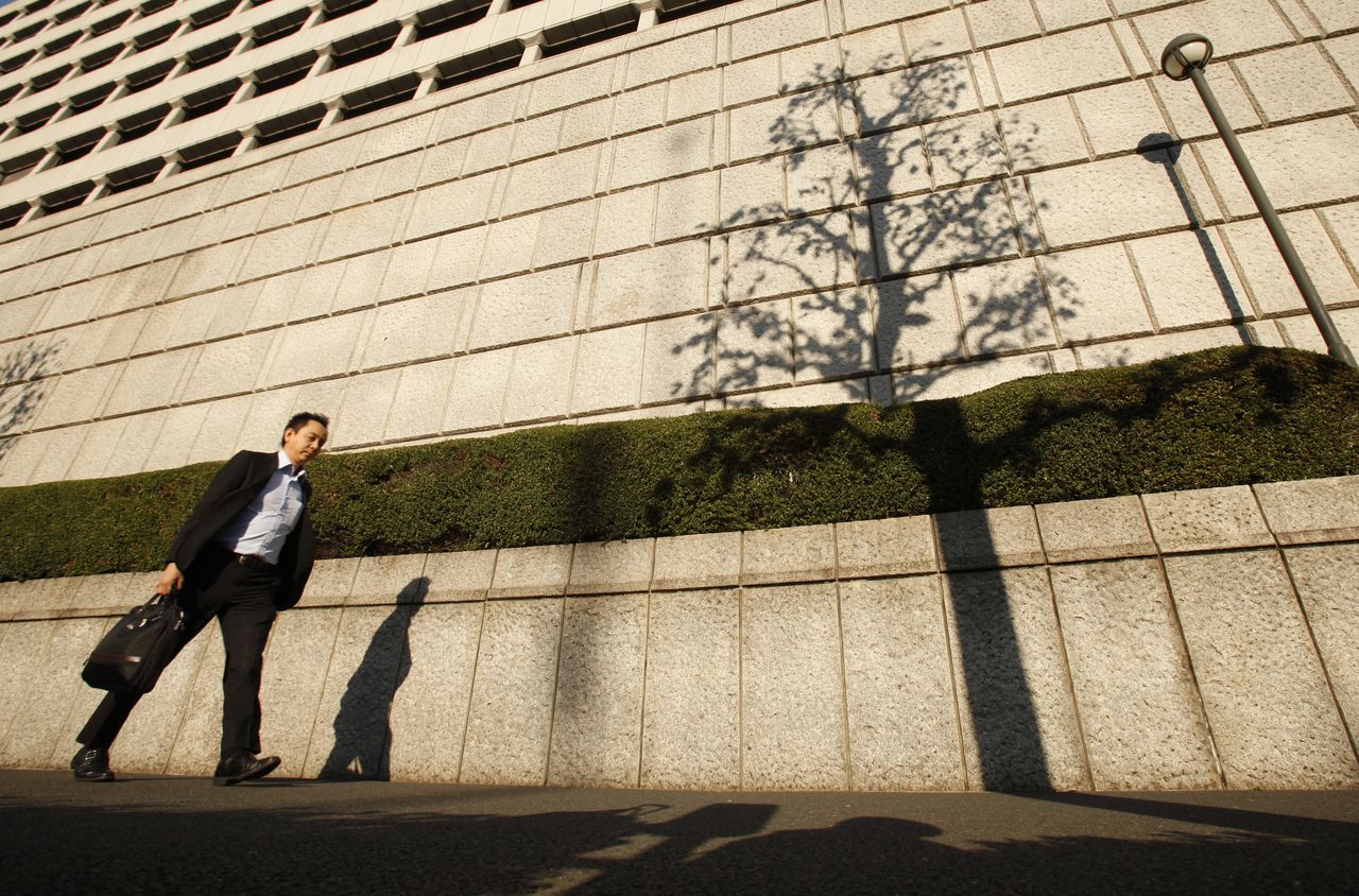 FILE PHOTO: A pedestrian walks past the Bank of Japan headquarters in Tokyo October 27, 2011. REUTERS/Yuriko Nakao