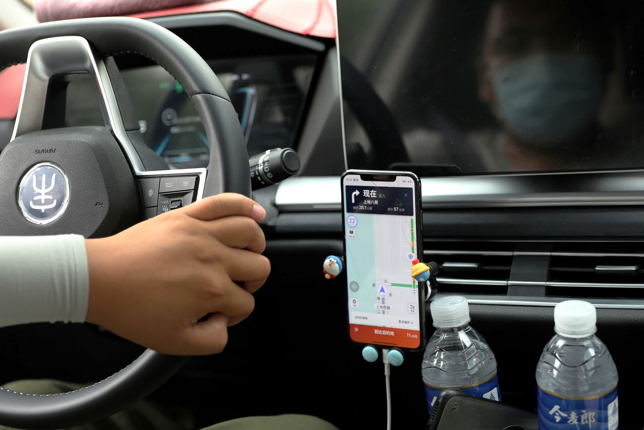 FILE PHOTO: A driver of Chinese ride-hailing service Didi drives with a phone showing a navigation map on Didi