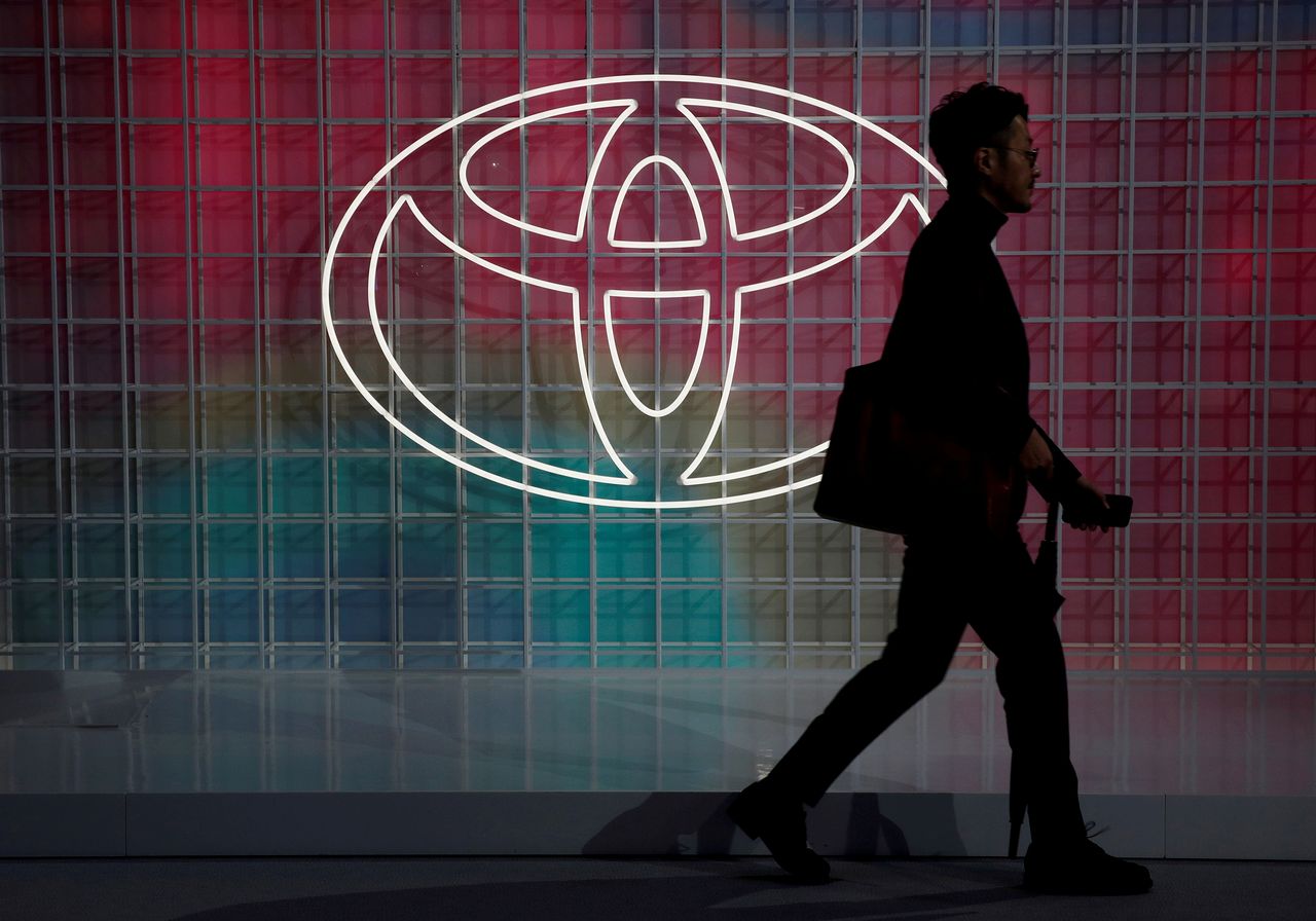 FILE PHOTO: A man walks past a Toyota logo at the Tokyo Motor Show, in Tokyo, Japan October 24, 2019. REUTERS/Edgar Su/File Photo