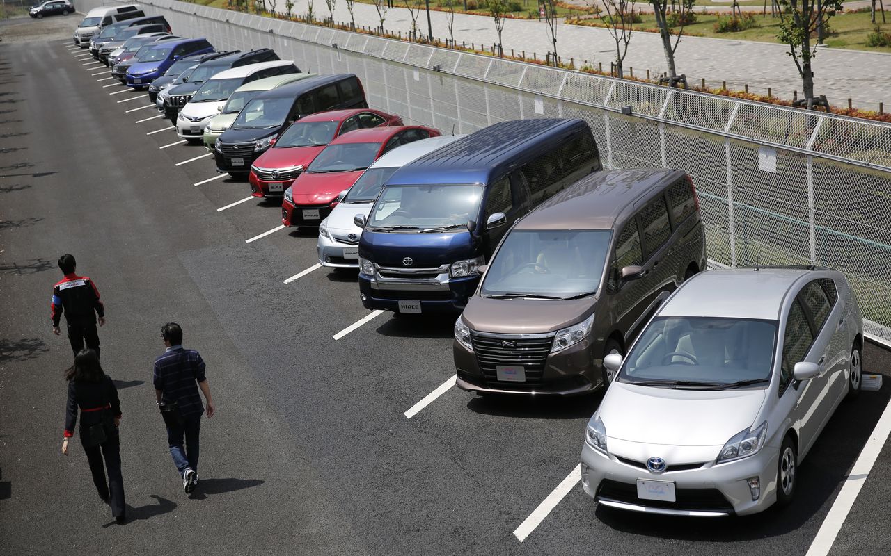 FILE PHOTO: People walk beside test-driving cars outside a car maker