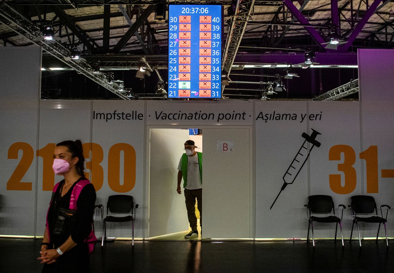 FILE PHOTO: A worker peers out of a door in front of COVID-19 vaccination booths at the Arena Treptow vaccination centre in Berlin, Germany, August 9, 2021. John Macdougall/Pool via REUTERS