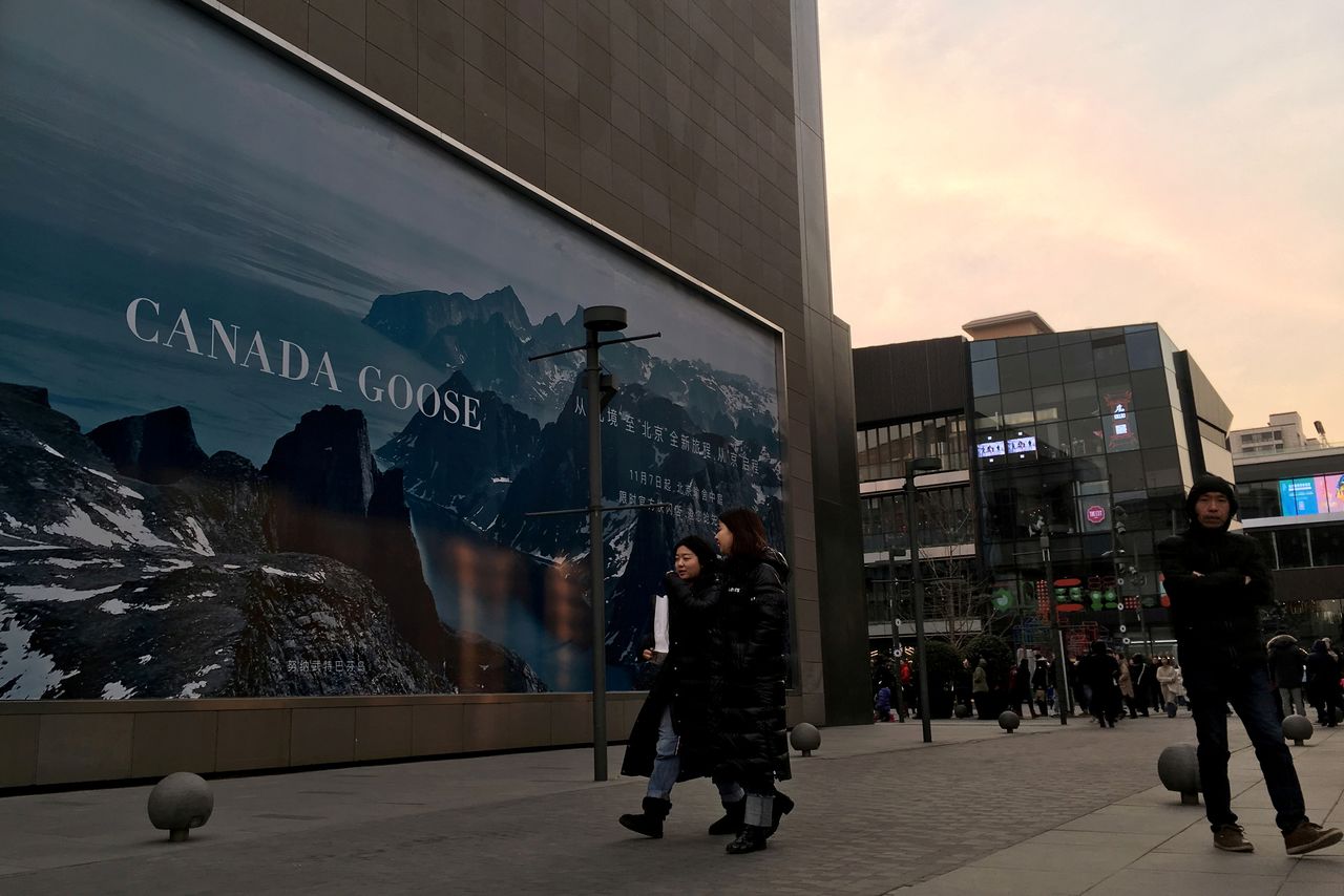 FILE PHOTO: People walk past an advertisement near the flagship store of Canadian luxury parka maker Canada Goose, in Sanlitun area of Beijing, China December 31, 2018. REUTERS/Martin Pollard