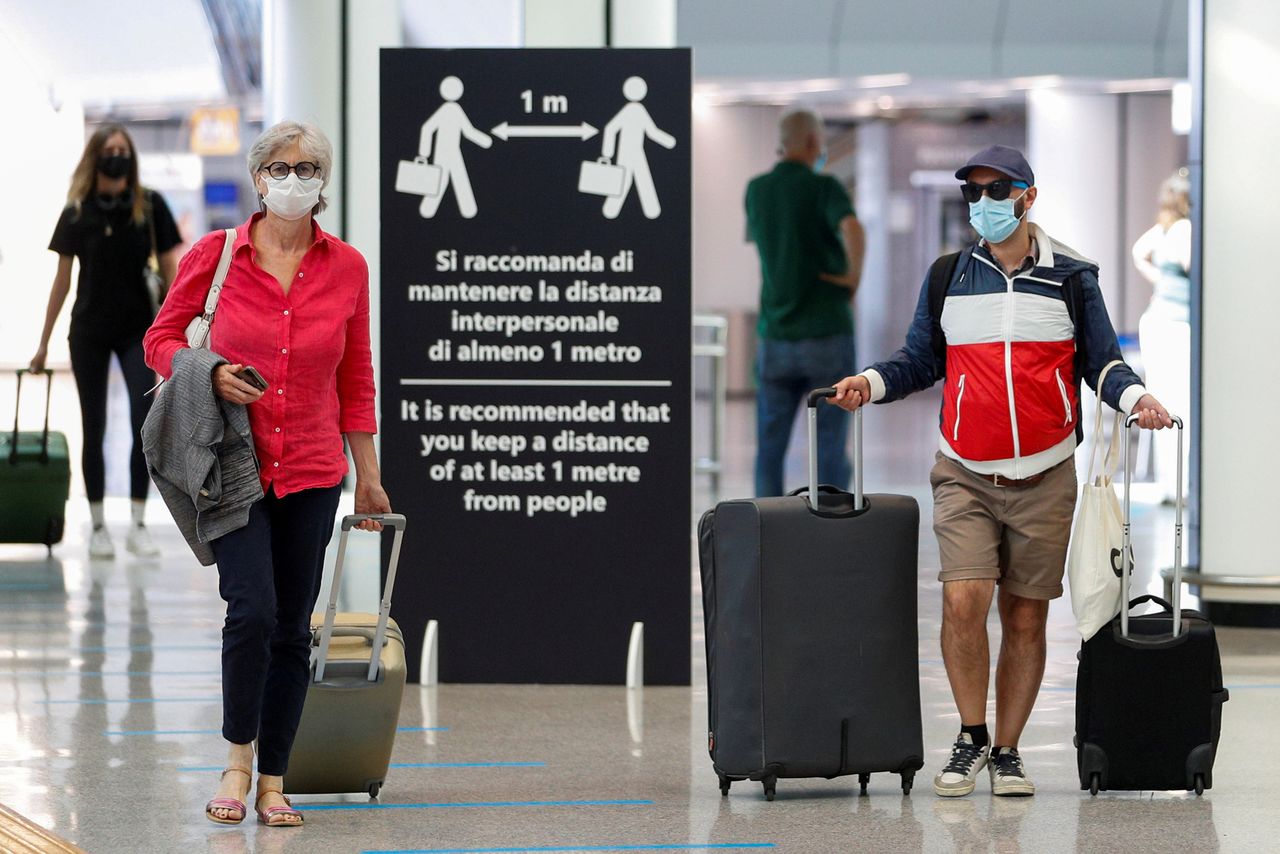 FILE PHOTO: Passengers wearing protective face masks walk at Fiumicino Airport on the day EU governments agreed a "safe list" of 14 countries for which they will allow non-essential travel starting from July, following the coronavirus disease (COVID-19) outbreak, in Rome, Italy, June 30, 2020. REUTERS/Guglielmo Mangiapane/File Photo