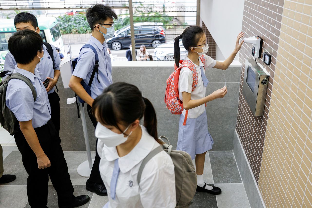 Secondary school students have their temperatures checked at the school entrance during the first day of the new term in Hong Kong, China September 1, 2021. Picture taken September 1, 2021. REUTERS/Tyrone Siu