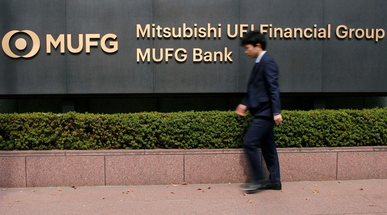 FILE PHOTO: A man walks past a signboard of Mitsubishi UFJ Financial Group and MUFG Bank at its headquarters in Tokyo, Japan April 3, 2018. REUTERS/Toru Hanai