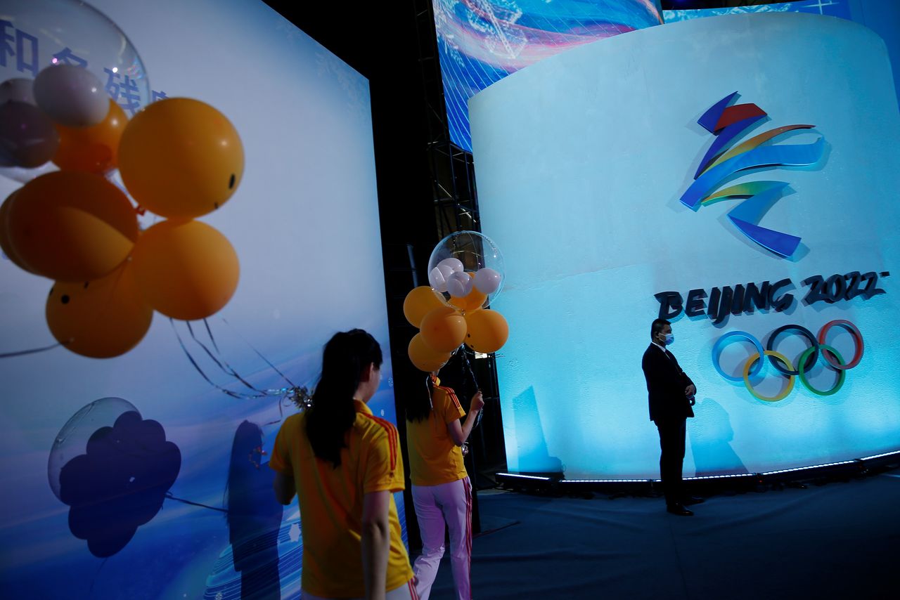 Attendees holding balloons walk past an emblem of the Beijing 2022 Winter Olympic Games at a ceremony unveiling the slogan in Beijing, China September 17, 2021. REUTERS/Tingshu Wang