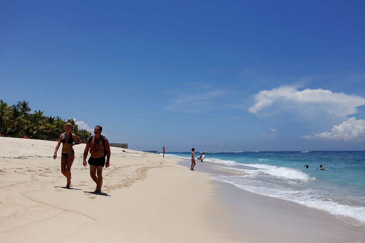 FILE PHOTO: Tourists walk along a beach in the luxury resort area of Nusa Dua ahead of Saudi Arabia