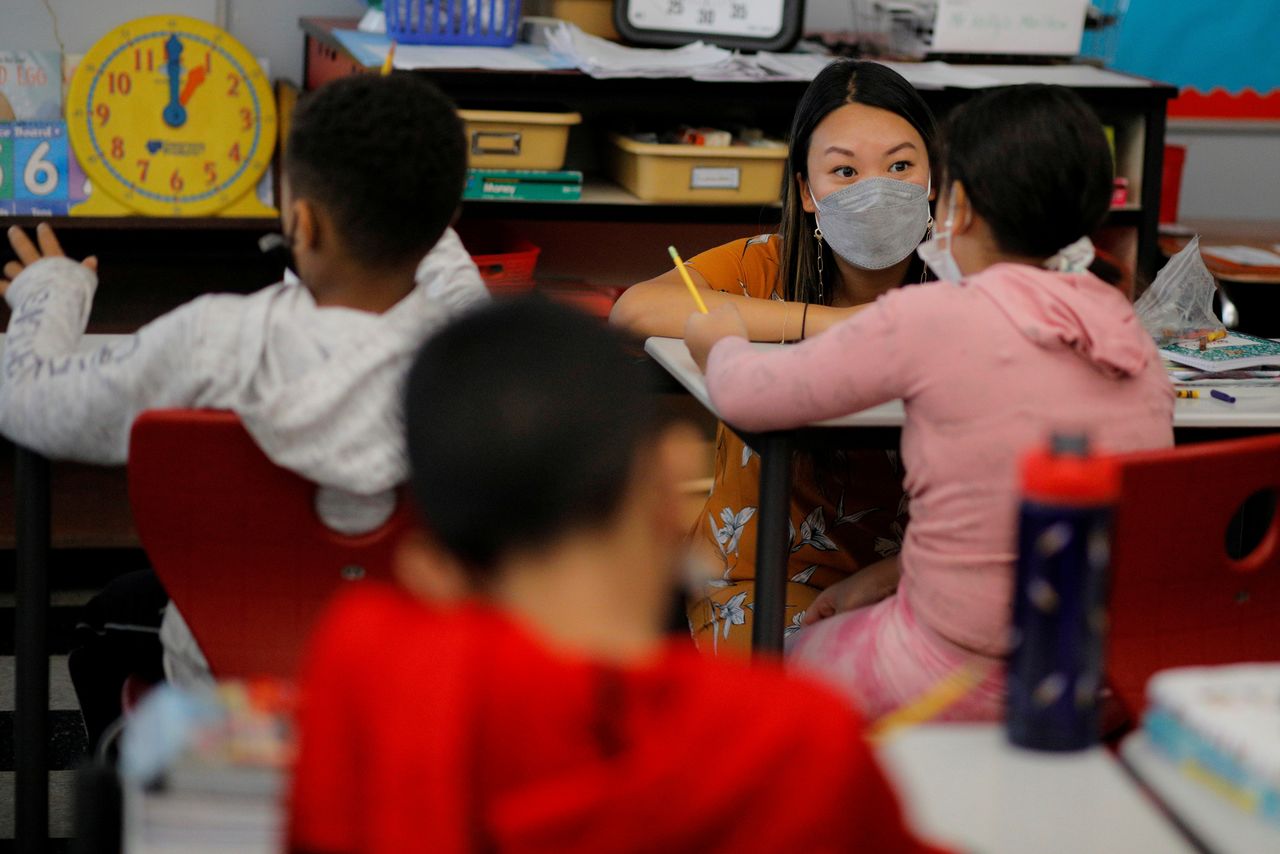 FILE PHOTO: Teacher Mary Yi works with a fourth grade student at the Sokolowski School, where students and teachers are required to wear masks because of the coronavirus disease (COVID-19) pandemic, in Chelsea, Massachusetts, U.S., September 15, 2021. REUTERS/Brian Snyder