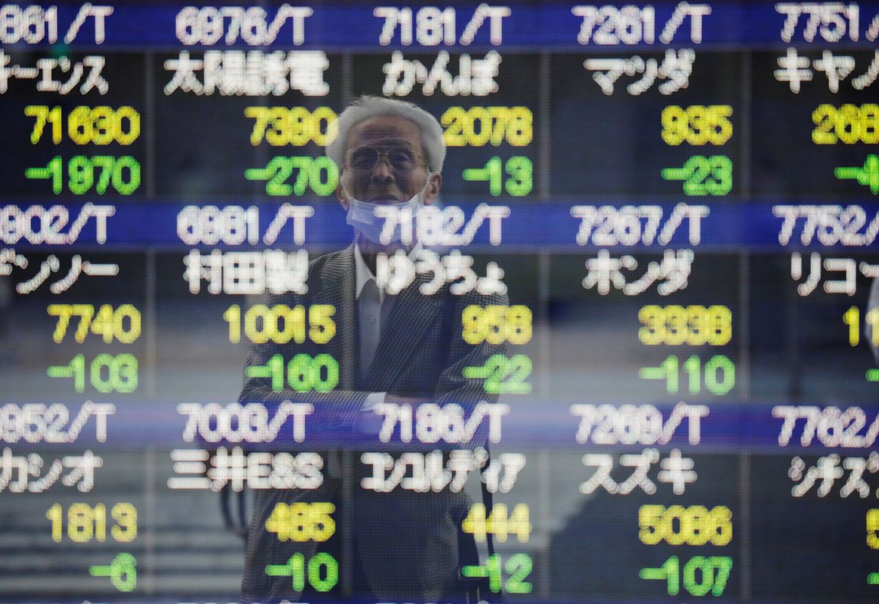 FILE PHOTO: A man wearing a protective mask, amid the COVID-19 outbreak, is reflected on an electronic board displaying stock prices outside a brokerage in Tokyo, Japan, September 21, 2021. REUTERS/Kim Kyung-Hoon