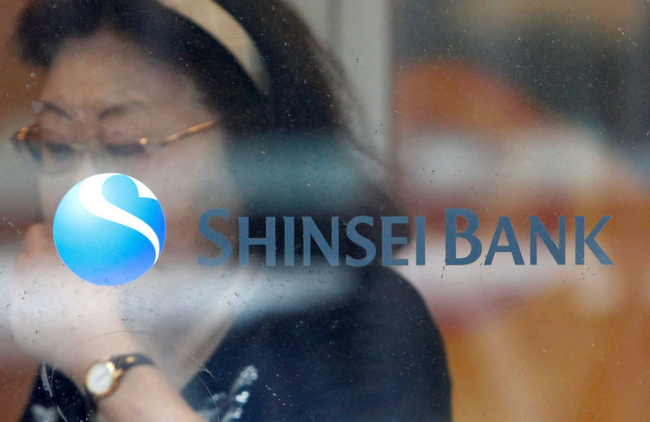 FILE PHOTO: A woman walks past a logo of the Shinsei Bank at its branch in Yokohama, south of Tokyo, June 23, 2010. REUTERS/Issei Kato/File Photo