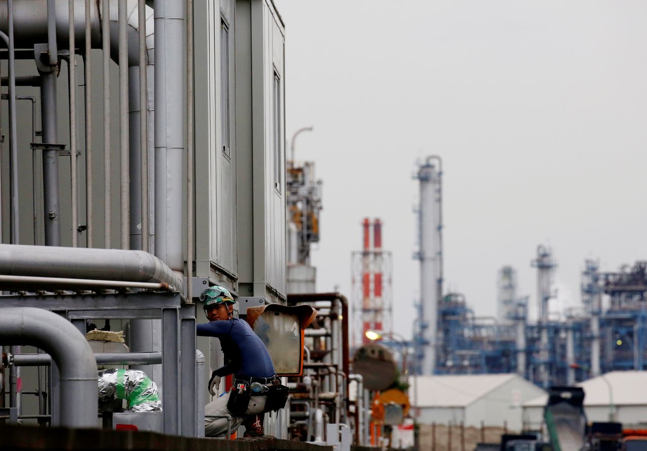 FILE PHOTO: A worker is seen in front of facilities and chimneys of factories at the Keihin Industrial Zone in Kawasaki, Japan September 12, 2018. REUTERS/Kim Kyung-Hoon