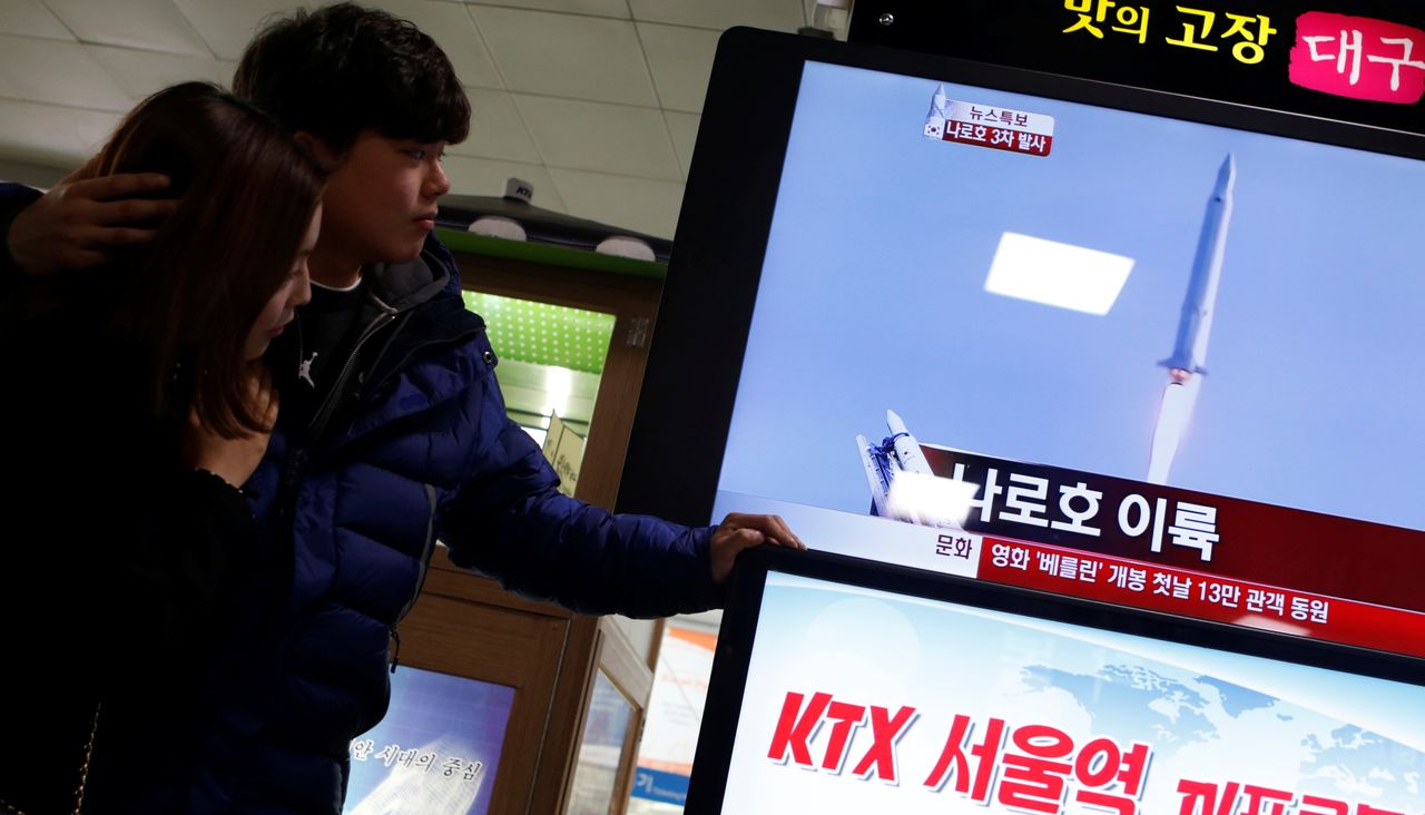 FILE PHOTO: A couple watch a television report broadcasting the launch of South Korea