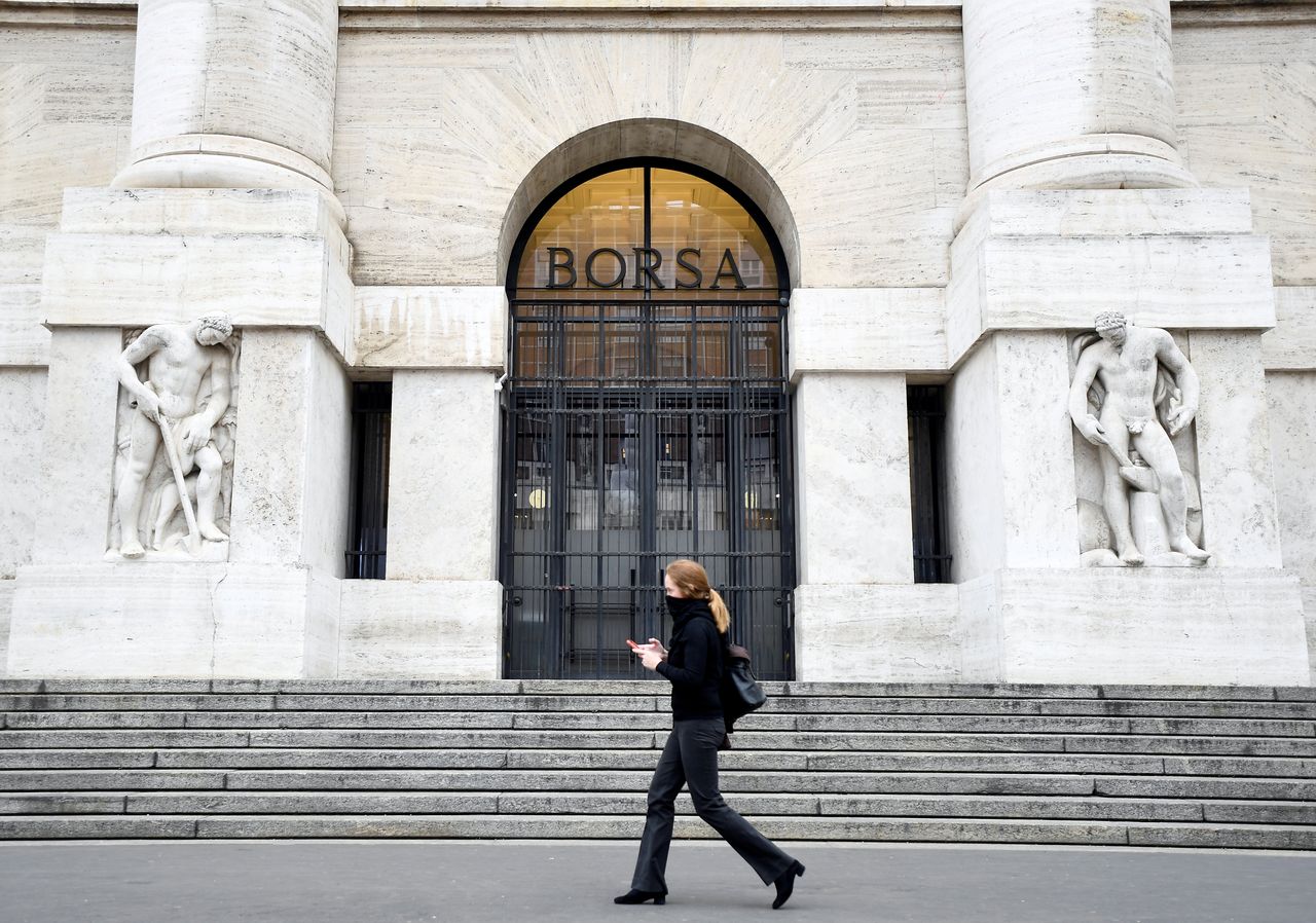 FILE PHOTO: A woman goes past the Italian Stock Exchange in Milan, as the country is hit by the coronavirus outbreak. Italy, February 25, 2020. REUTERS/Flavio Lo Scalzo/File Photo
