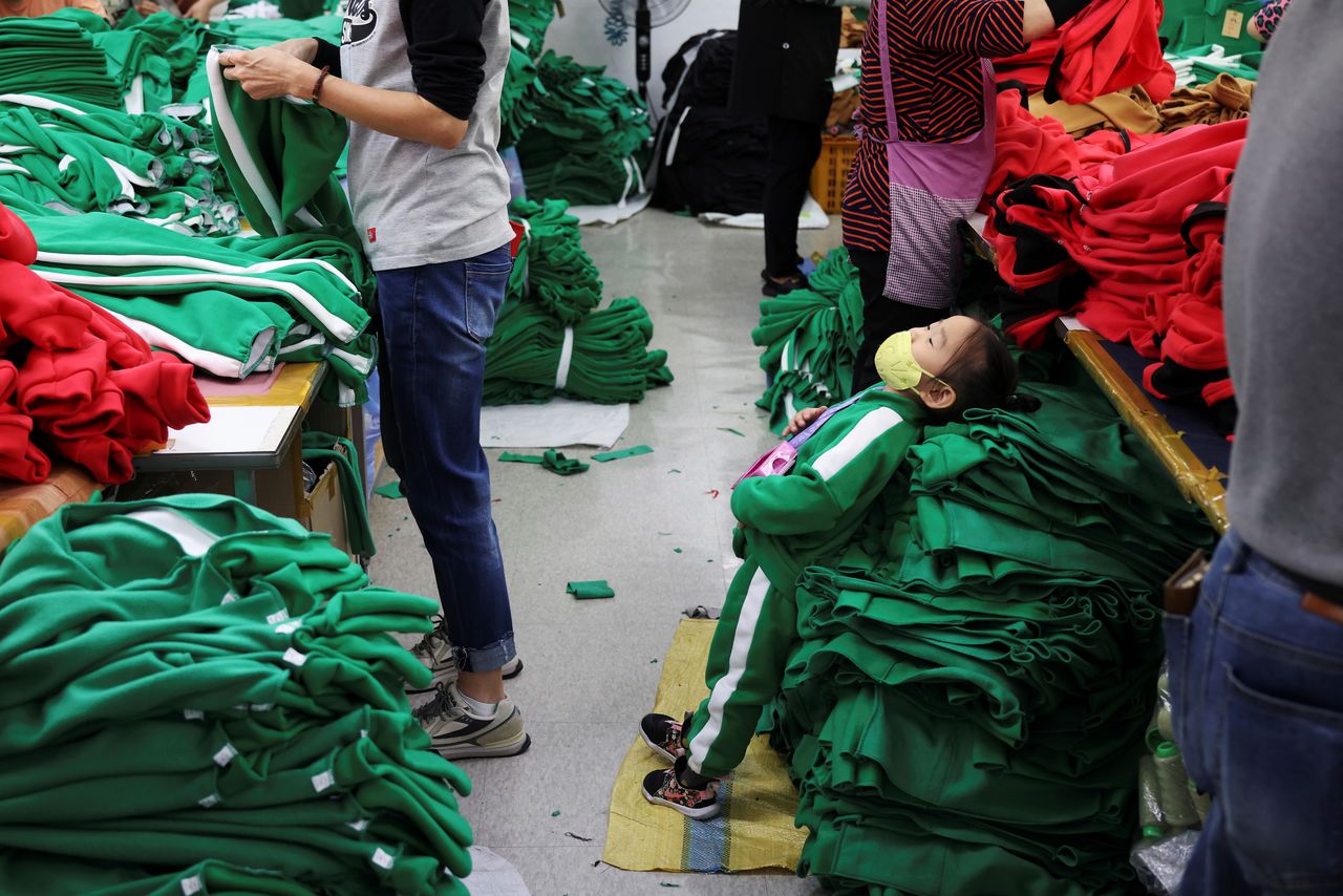 A granddaughter of clothing factory owner Ko Jong-hyun leans on tracksuits inspired by Netflix series "Squid Game" at his plant in Seoul, South Korea, October 21, 2021. Picture taken on October 21, 2021. REUTERS/Kim Hong-Ji