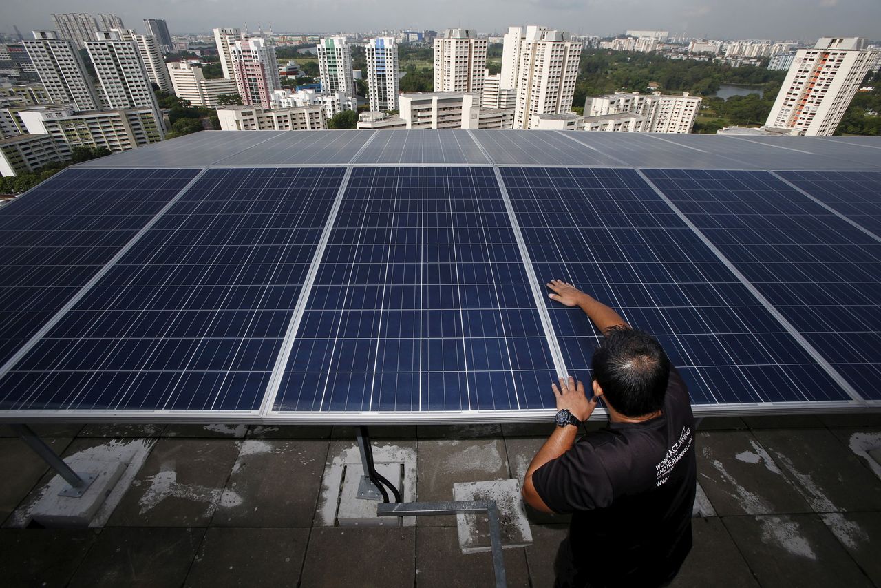 FILE PHOTO: Maintenance officer Wilson Ting of Sunseap Leasing inspects photovoltaic solar modules on top of a block of Housing Development Board (HDB) public housing estate apartments in Singapore April 15, 2015. REUTERS/Edgar Su