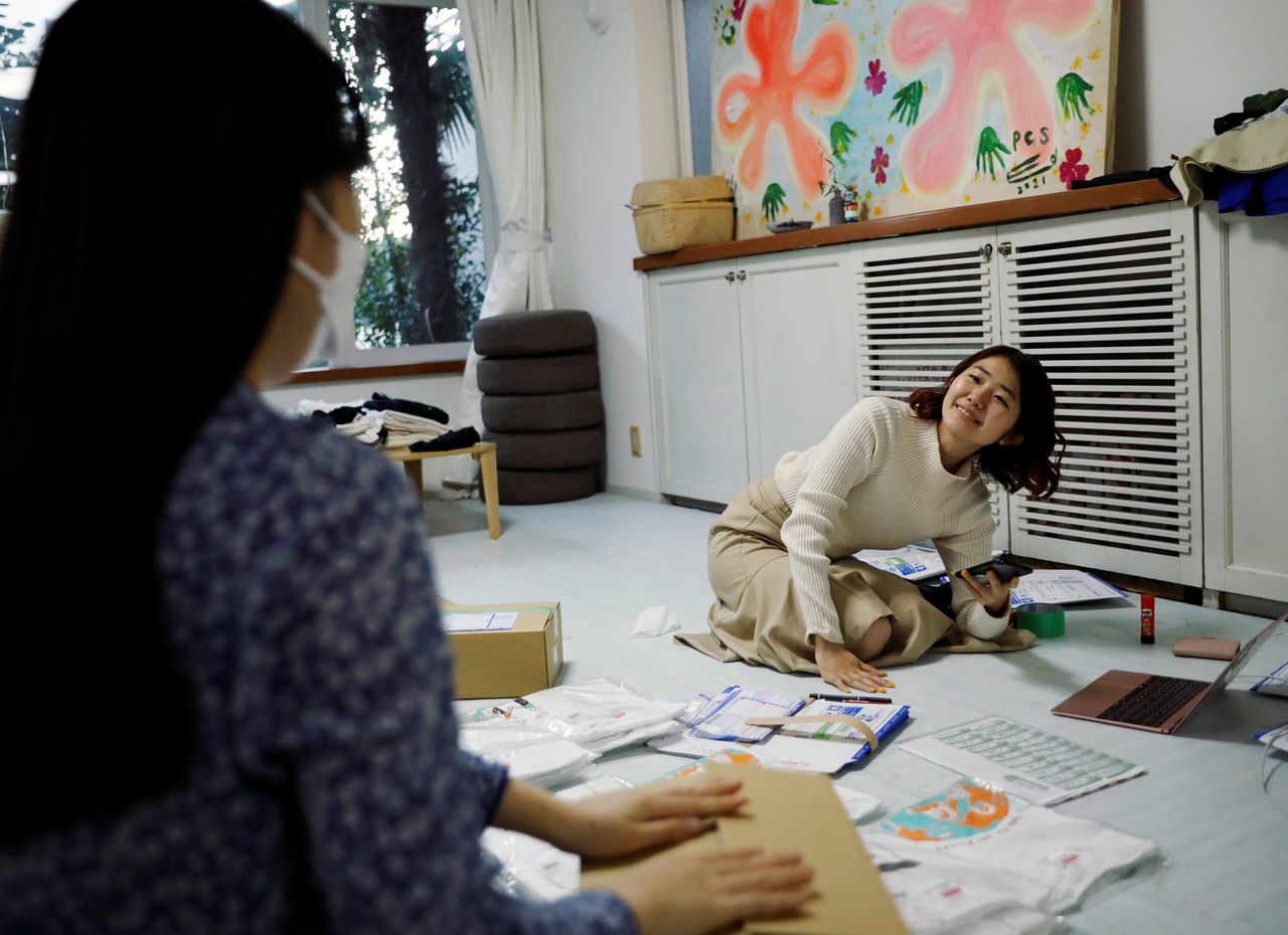 Youth activist and representative of "No Youth No Japan", Momoko Nojo, chats with a group member Ayumi Adachi (20), as they carry out shipping work of T-shirts for a campign to urge young people to vote during elections, in Tokyo, Japan October 20, 2021. REUTERS/Issei Kato