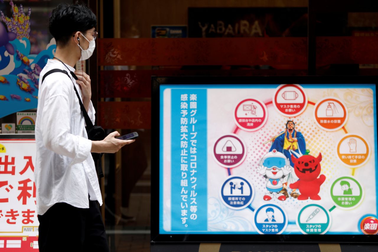 FILE PHOTO: A man looks at infection prevention information in Shibuya shopping area, during a state of emergency amid the coronavirus disease (COVID-19) outbreak, in Tokyo, Japan August 29, 2021. REUTERS/Androniki Christodoulou