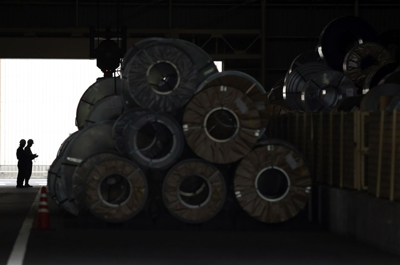 FILE PHOTO: Workers control a crane to move a steel coil inside a factory in Tokyo May 29, 2014. REUTERS/Yuya Shino