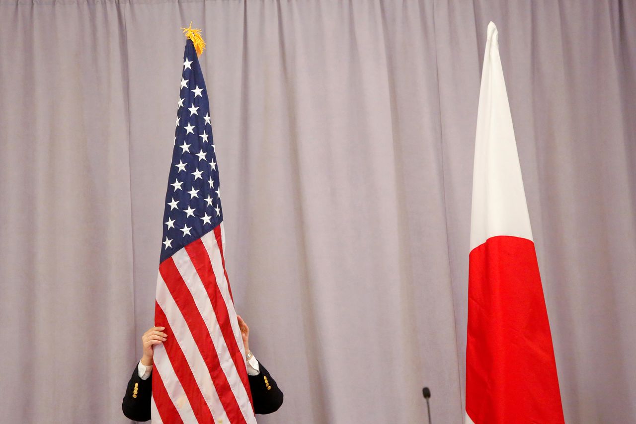 FILE PHOTO: A worker adjusts the U.S. flag before Japanese Prime Minister Shinzo Abe addresses media following a meeting with President-elect Donald Trump in Manhattan, New York, U.S., November 17, 2016. REUTERS/Andrew Kelly