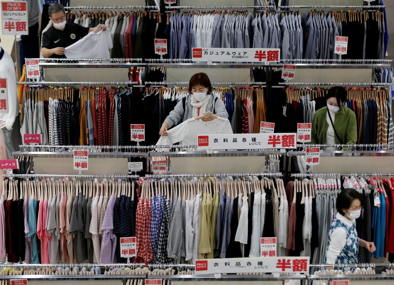 FILE PHOTO: Shoppers wearing protective masks choose clothes at Japan