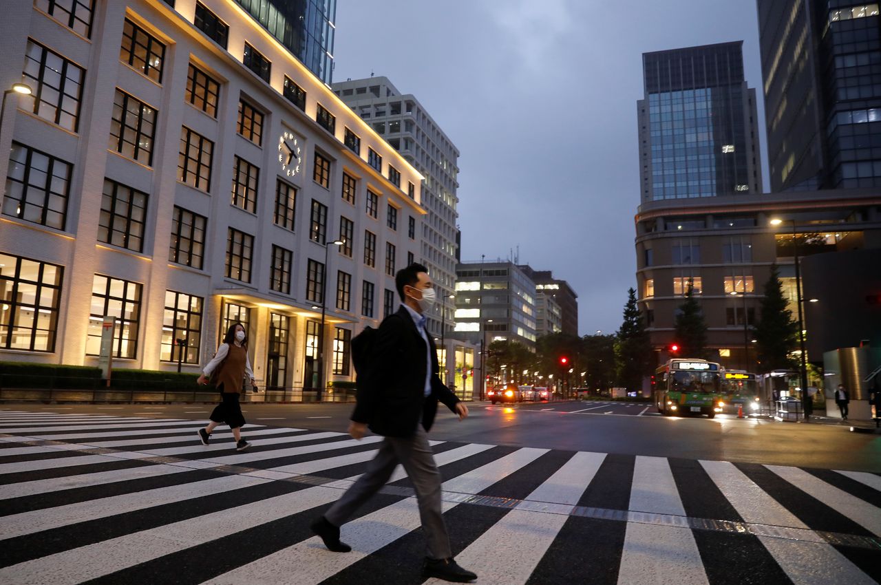 FILE PHOTO: A pedestrian wearing a protective face mask crosses a street, amid the coronavirus disease (COVID-19) outbreak, in the business district in Tokyo, Japan, May 21, 2020.REUTERS/Kim Kyung-Hoon