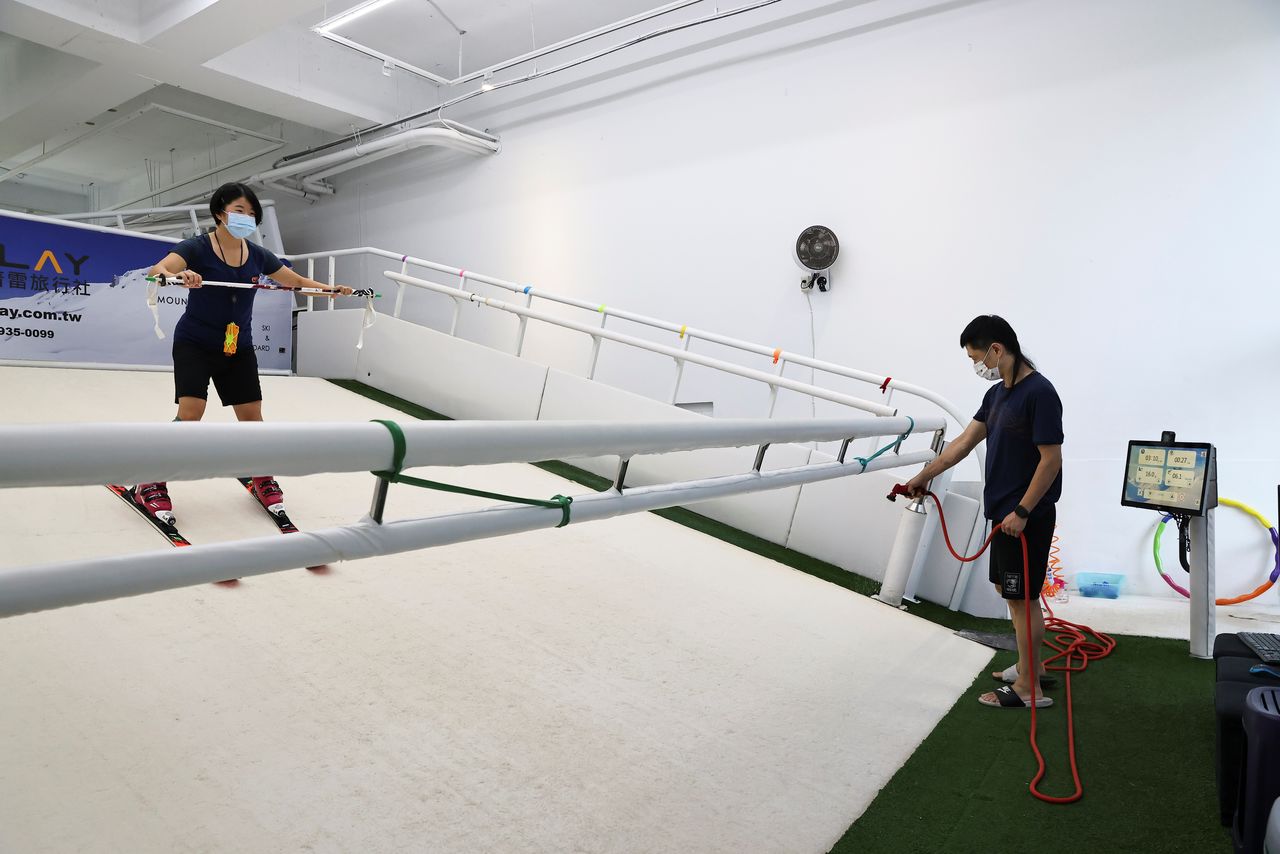 Lee Win-yi, 19, a Taiwanese Alpine skier, trains on a machine with the help of her father Ader Lee, at the family