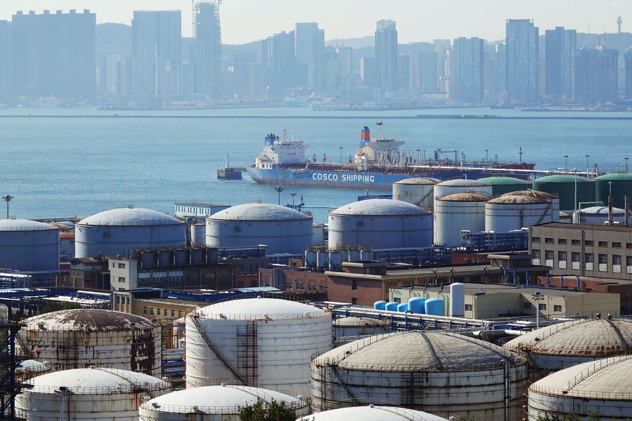 FILE PHOTO: A China Ocean Shipping Company (COSCO) vessel is seen near oil tanks at the China National Petroleum Corporation (CNPC)