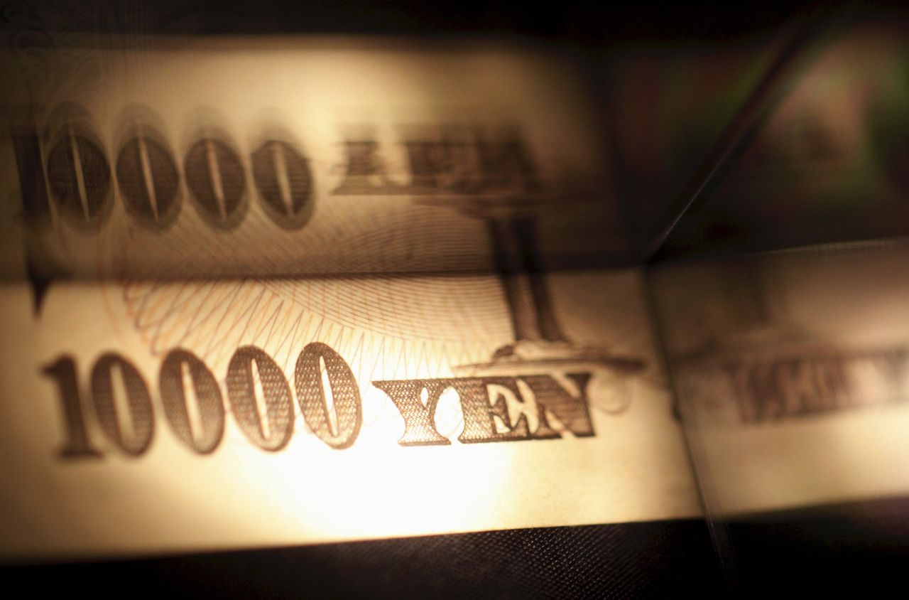 FILE PHOTO: Light is cast on a Japanese 10,000 yen note as it