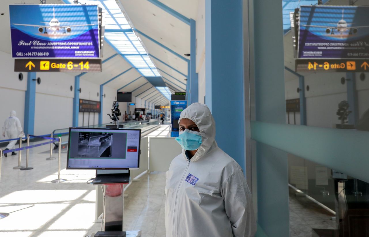 FILE PHOTO: A security officer wearing protective gear stands next to passenger temperature scanning machine where she is on duty as Sri Lanka