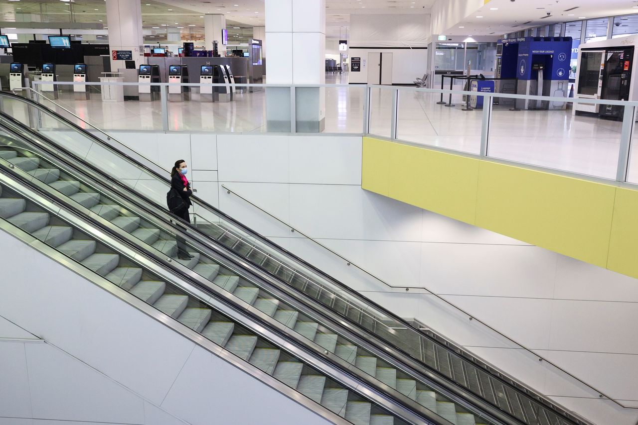 FILE PHOTO: A flight crew member stands on an escalator in the international terminal at Sydney Airport, as countries react to the new coronavirus Omicron variant amid the coronavirus disease (COVID-19) pandemic, in Sydney, Australia, November 30, 2021. REUTERS/Loren Elliott