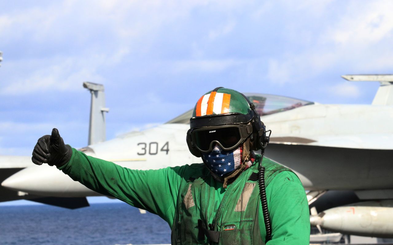 A flight deck crew member signals to colleagues on the USS Carl Vinson in Western Pacific, south of Japan, November 30, 2021. REUTERS/Tim Kelly