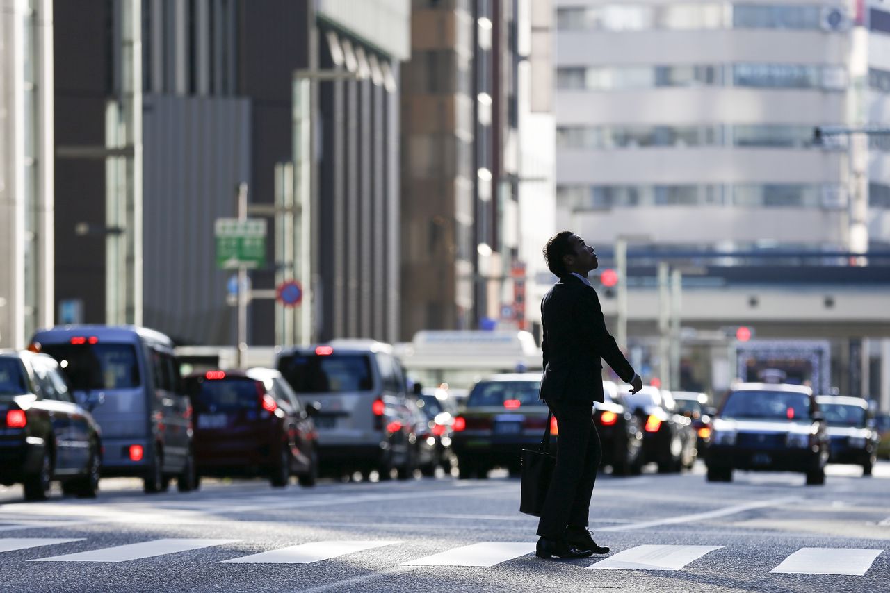 FILE PHOTO: A businessman looks up as he crosses a street in a business district in central Tokyo, Japan, December 8, 2015. Japan