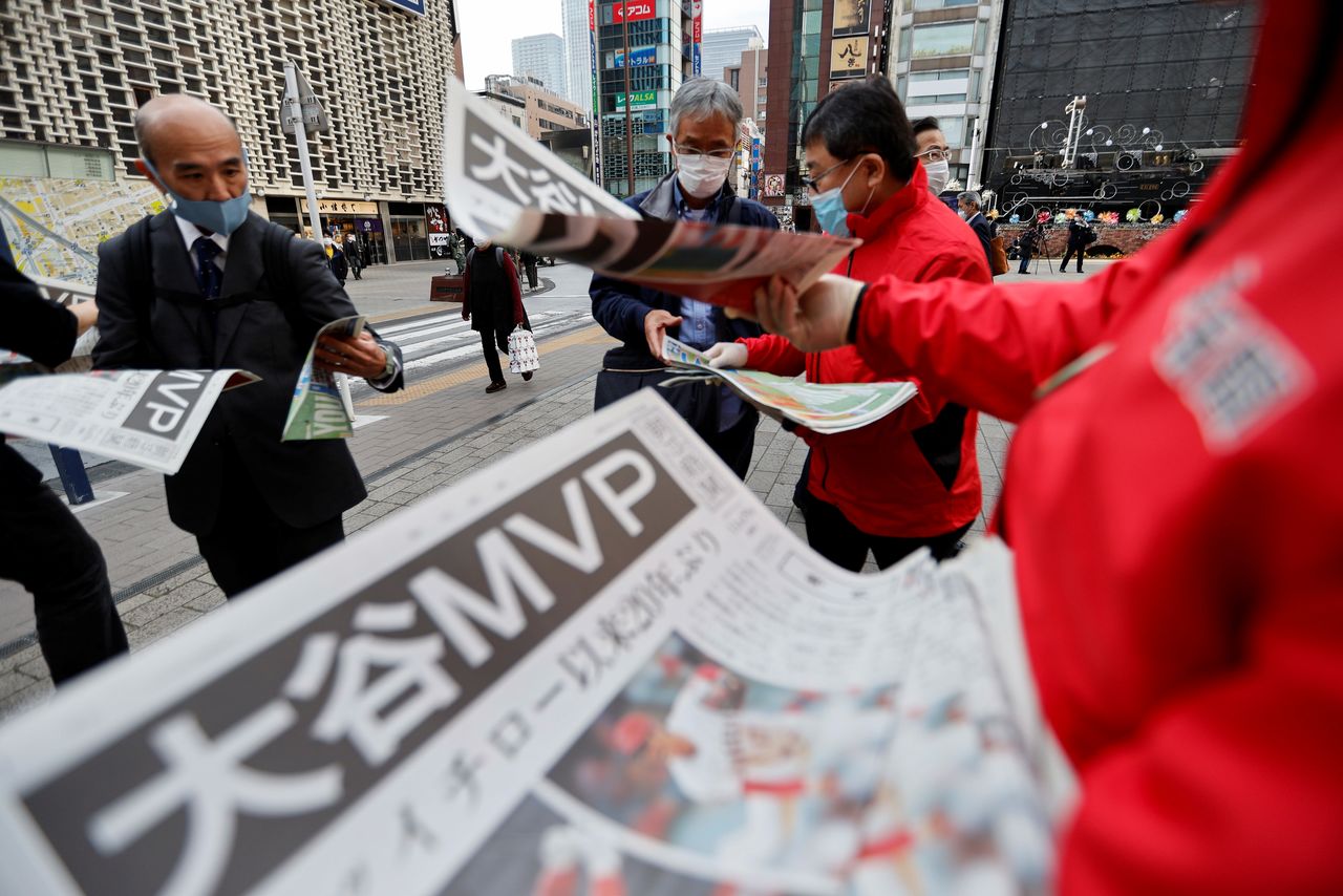 FILE PHOTO: People receive extra editions of a newspaper, reporting Japan