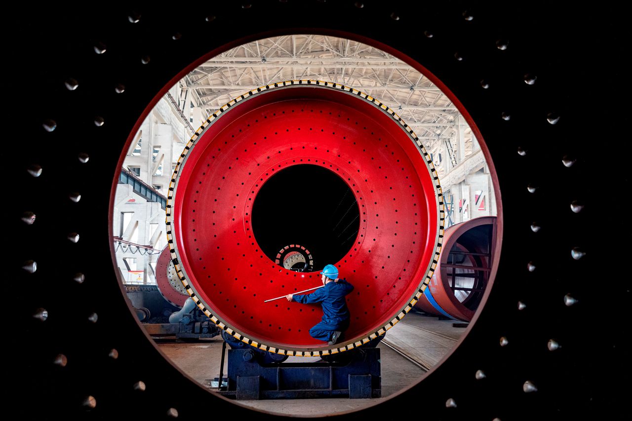 FILE PHOTO: An employee measures a newly manufactured ball mill machine at a factory in Nantong, Jiangsu province, China June 28, 2019. REUTERS/Stringer