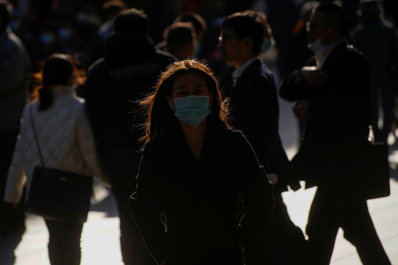 A woman wearing a protective mask walks on a street, following the new cases of the coronavirus disease (COVID-19), in Shanghai, China, December 1, 2021. REUTERS/Aly Song