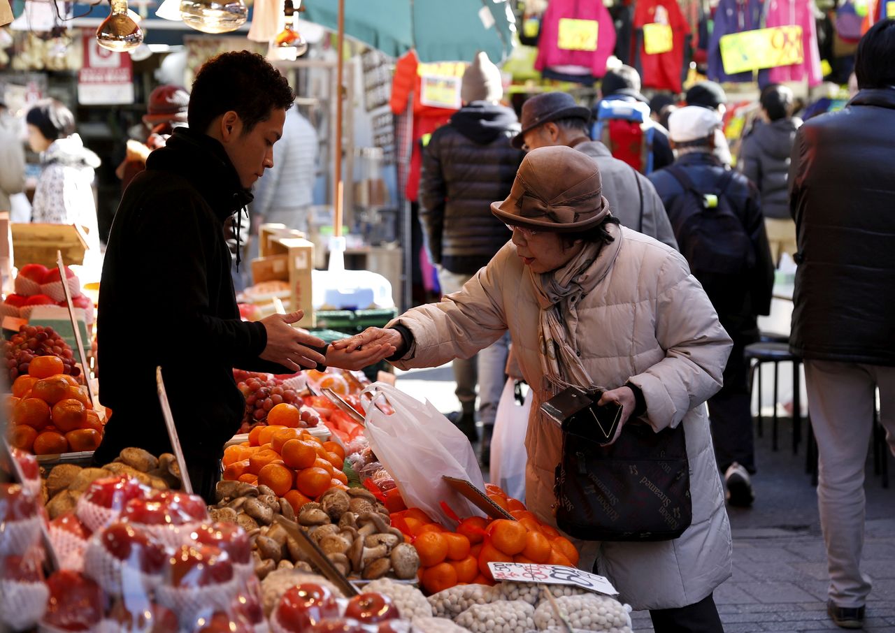 FILE PHOTO: A woman pays money as she buys fruits outside a vegetable store at Ameyoko shopping district in Tokyo, Japan, January 27, 2016. REUTERS/Yuya Shino/File Photo/File Photo