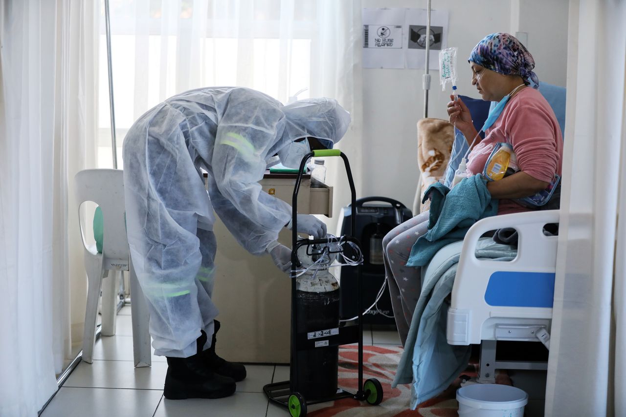 FILE PHOTO: A healthcare worker assists a patient being treated at a makeshift hospital run by charity organisation The Gift of the Givers, during the coronavirus disease (COVID-19) outbreak in Johannesburg, South Africa, July 11, 2021.  REUTERS/ Sumaya Hisham