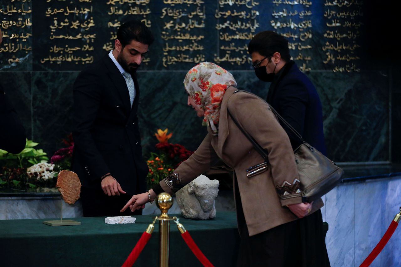 Officials look at The Gilgamesh Dream Tablet, stolen from Iraq in 1991 and returned after it was seized by the U.S. government, and other artefacts displayed at the Ministry of Foreign Affairs in Baghdad, Iraq December 7, 2021. REUTERS/Saba Kareem