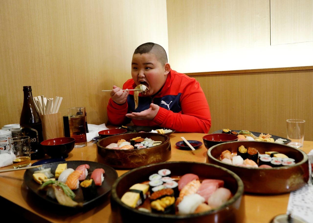 Elementary school sumo wrestler Kyuta Kumagai eats lunch with his mother (not seen) after he lost in a tournament of the All-Japan Elementary School Sumo Championship at Ryogoku Kokugikan National Sumo Stadium in Tokyo, Japan, December 5, 2021. REUTERS/Kim Kyung-Hoon