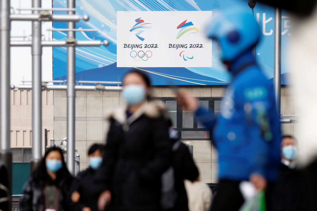 Pedestrians walk past the emblems of Beijing 2022 Winter Olympic and Paralympic Games near a flagship merchandise store for the Beijing 2022 Winter Olympics in Beijing, China December 8, 2021. REUTERS/Carlos Garcia Rawlins
