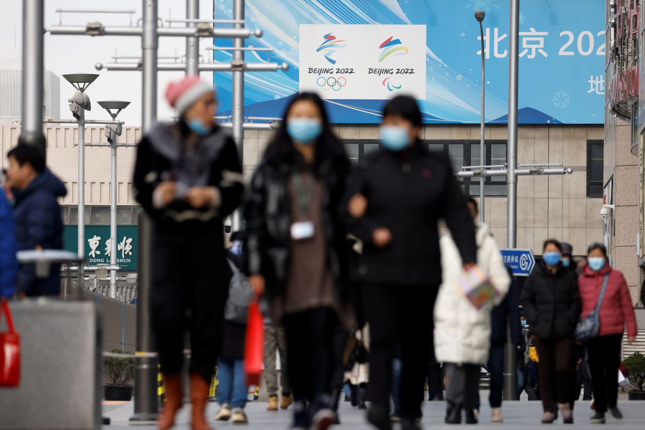 Pedestrians walk past the emblems of Beijing 2022 Winter Olympic and Paralympic Games near a flagship merchandise store for the Beijing 2022 Winter Olympics in Beijing, China December 8, 2021. REUTERS/Carlos Garcia Rawlins
