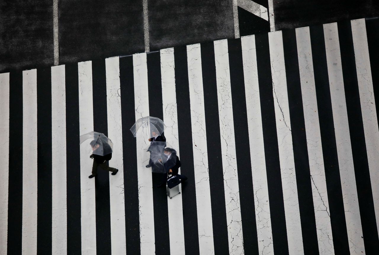 Men wearing protective face masks walk on a pedestrian crossing, amid the coronavirus disease (COVID-19) pandemic, in Tokyo, Japan December 8, 2021. REUTERS/Issei Kato