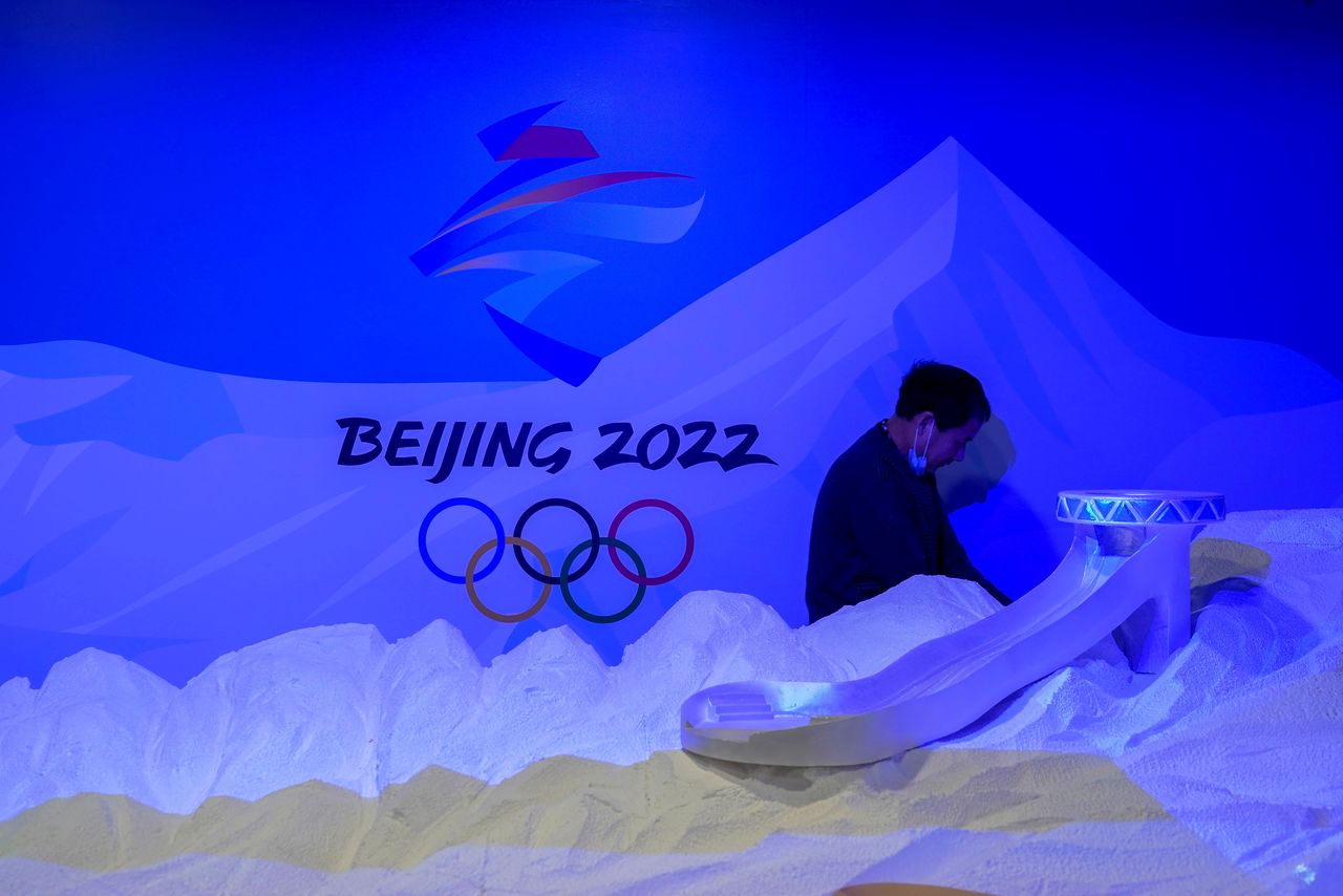 A staff member works near the emblem for Beijing 2022 Winter Olympics displayed at the Shanghai Sports Museum in Shanghai, China, December 8, 2021. REUTERS/Aly Song