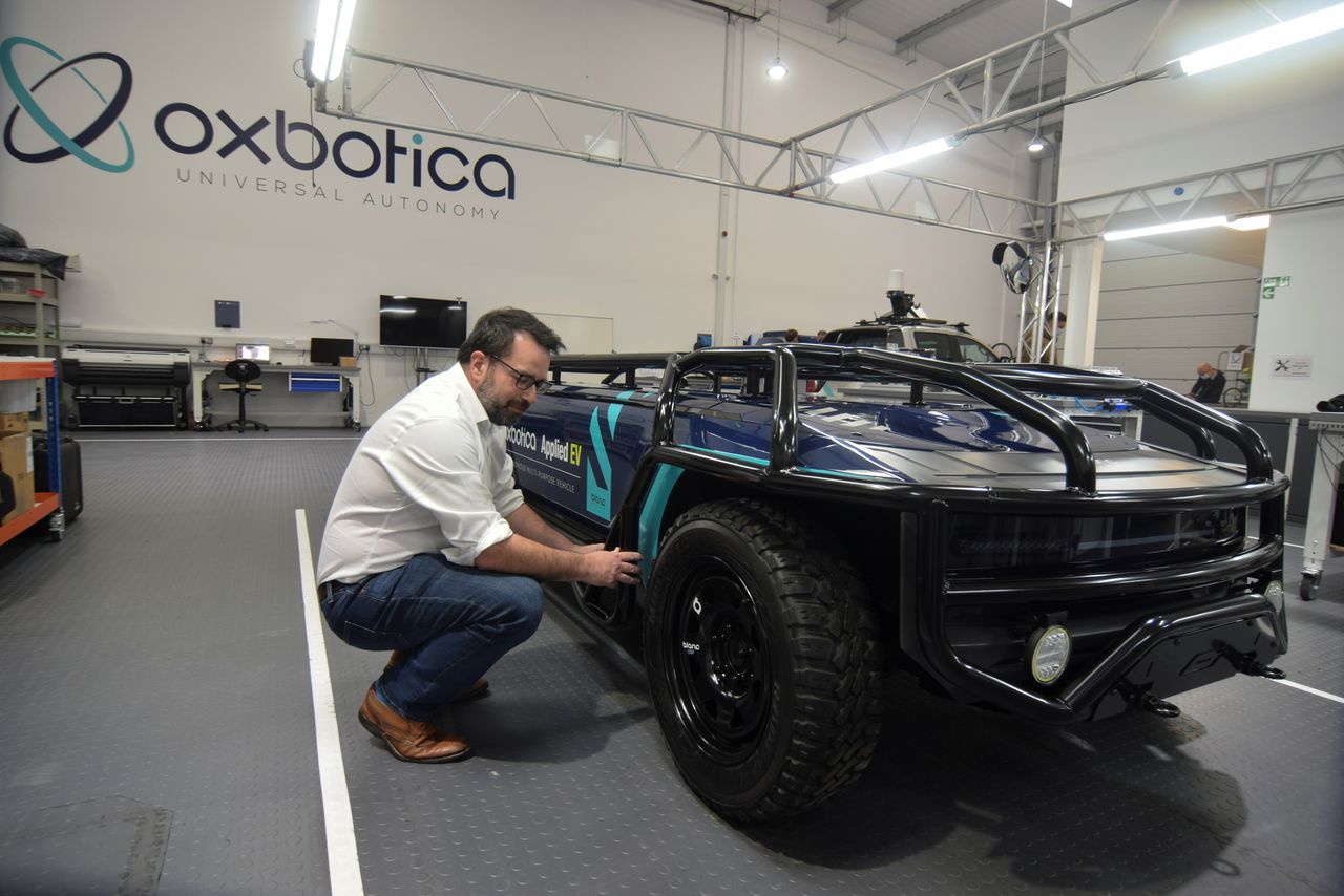 Paul Newman, founder of British autonomous vehicle software startup Oxbotica, is seen next to a converted pickup truck that has been used for test self-driving operations with a mining company, in Oxford, Britain, October 22, 2021. REUTERS/Nick Carey