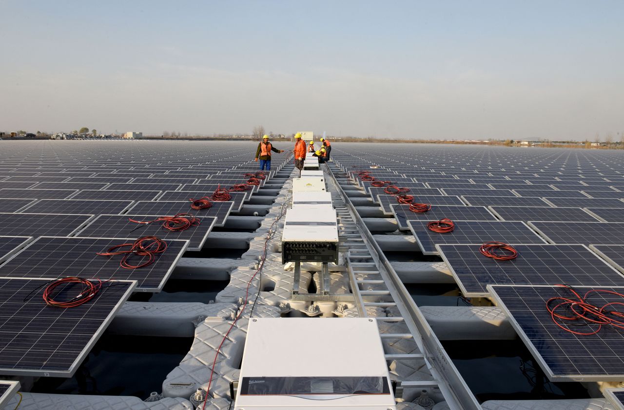 FILE PHOTO: Workers install solar panels at a floating solar plant developed by China