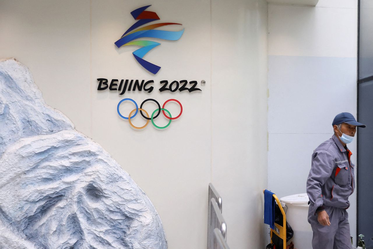 A cleaning worker walks past a logo of the Beijing 2022 Winter Olympics inside the Olympic Tower, in Beijing, China December 10, 2021. REUTERS/Tingshu Wang