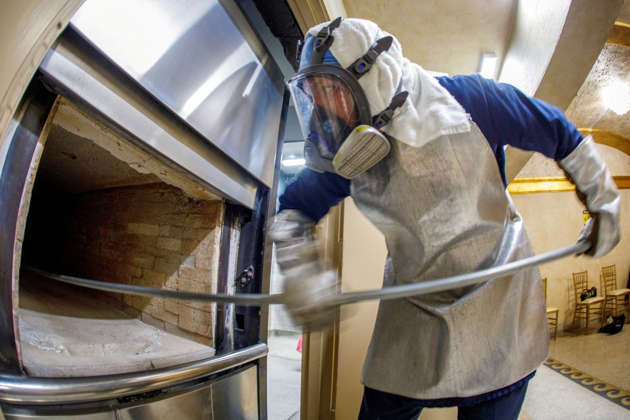 FILE PHOTO: Funeral coordinator and crematory technician Eddie Martinez collects remains from a cremation furnace at the Hollywood Forever cemetery as it struggles to keep up with demand during the outbreak of coronavirus disease (COVID-19) in Los Angeles, California, U.S., March 3, 2021. Picture taken March 3, 2021. REUTERS/Mike Blake/File Photo