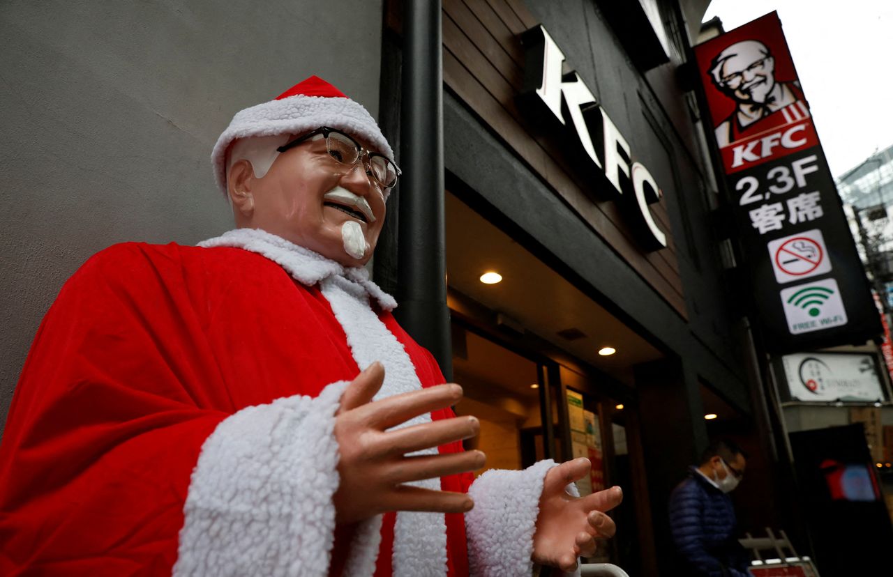 A man wearing a protective mask, amid the coronavirus disease (COVID-19) outbreak, walks past a Colonel Sanders statue dressed as Santa Claus at a Kentucky Fried Chicken (KFC) restaurant in Tokyo, Japan, December 14, 2021. REUTERS/Kim Kyung-Hoon