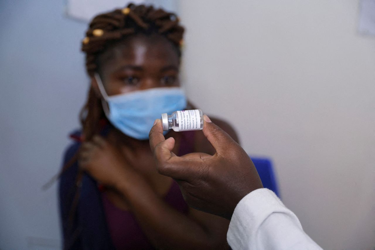 FILE PHOTO: A health worker shows a woman a vial containing a COVID-19 vaccine before administering it to her, at the Penda health center in Nairobi, Kenya, December 9, 2021. REUTERS/Baz Ratner