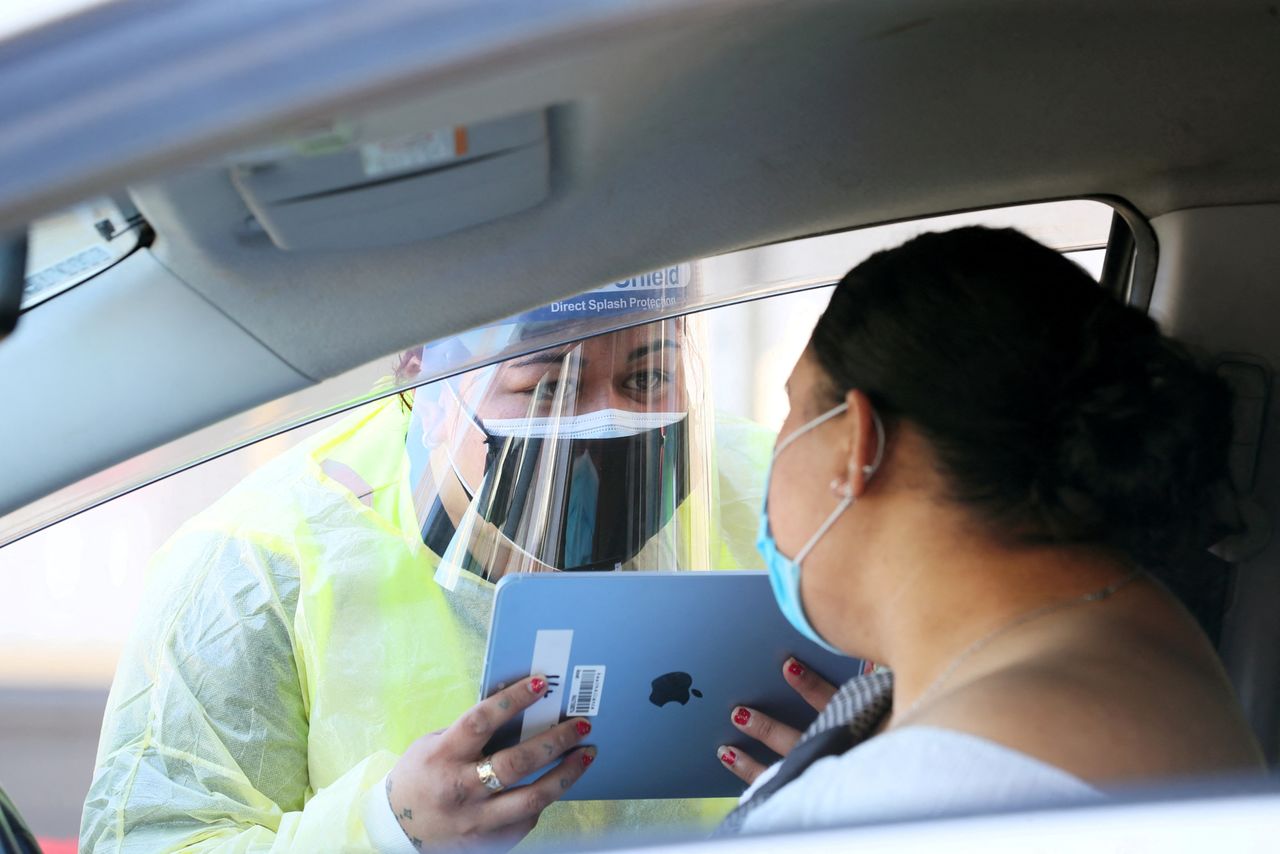 FILE PHOTO: A member of the public gives information to a health worker at a drive-through coronavirus disease (COVID-19) vaccination clinic in Otara during a single-day vaccination drive, aimed at significantly increasing the percentage of vaccinated people in the country, in Auckland, New Zealand, October 16, 2021.  REUTERS/Simon Watts